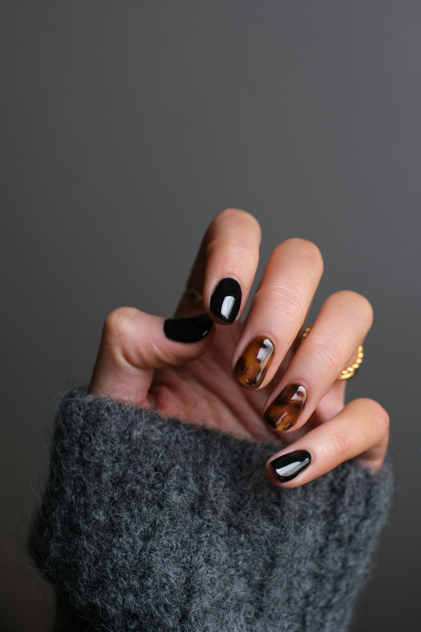 A hand with glossy black and tortoiseshell gel nails